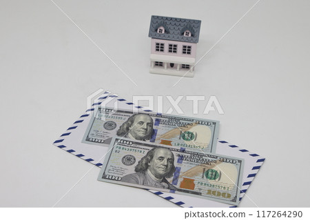 Banknotes in a white envelope and a toy house, funds for the purchase of real estate. Banknotes in a white envelope and a toy house, funds for the purchase of real estate. 117264290