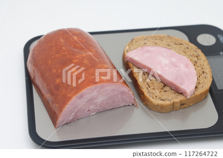 Sliced boiled delicious sausage on electronic scales, calorie counting, proper nutrition. Sliced boiled delicious sausage on electronic scales, calorie counting, proper nutrition. 117264722