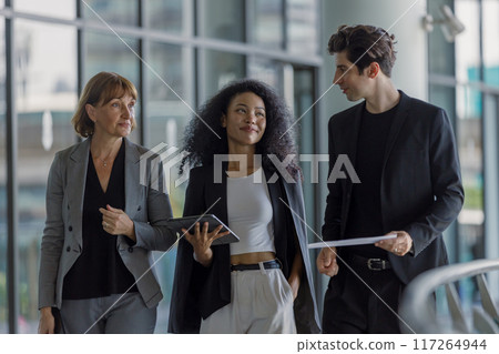 Diverse group businesspeople walking to meeting at modern office. 117264944