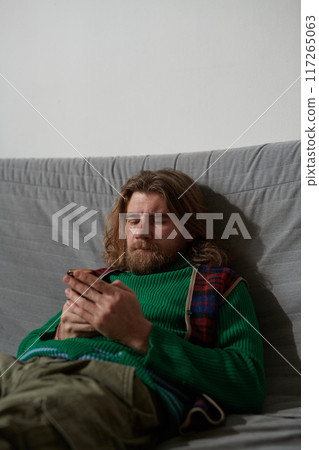 Bearded Man Wearing Sweater While Sitting on Couch Bearded Man Wearing Sweater While Sitting on Couch 117265063