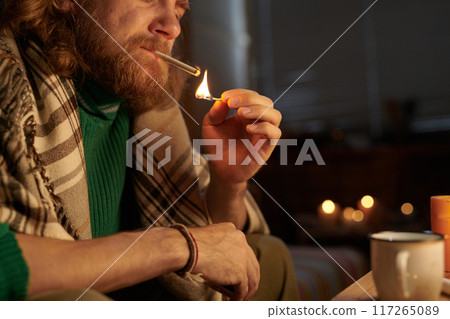 Lighting Cigarette Indoors with Candlelight Ambiance 117265089