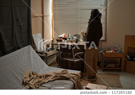 Woman Standing in Cozy Bedroom Looking Out Window 117265180