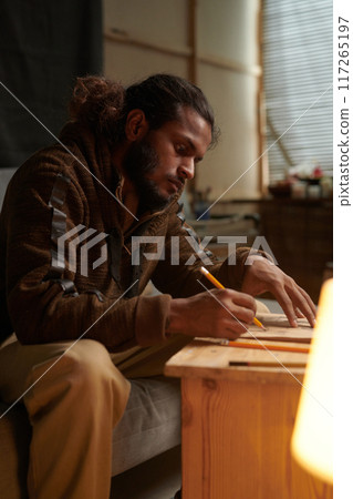 Focused Man Sketching in Art Studio Creating Artwork 117265197