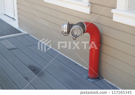 A Bright Red Fire Hydrant Attachment Installed on a Wooden Deck in an Urban Area 117265345