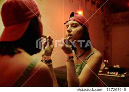 Applying lipstick in front of mirror 117265646
