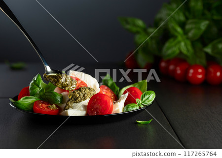 Mozzarella with basil, cherry tomatoes and pesto sauce. 117265764