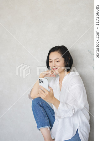 A woman operating a smartphone in a room 117266085