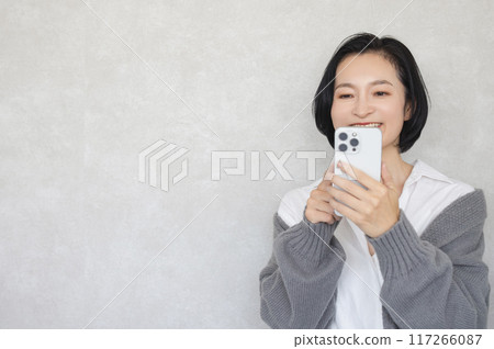 A woman operating a smartphone in a room 117266087