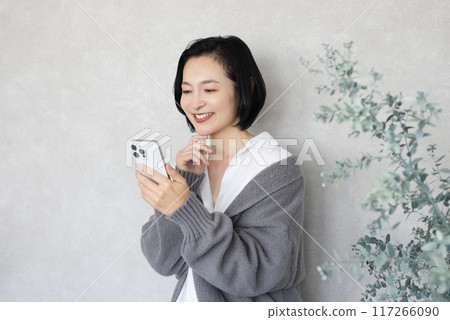 A woman operating a smartphone in a room 117266090