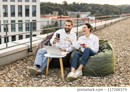 Colleagues working and laughing on office rooftop Colleagues working and laughing on office rooftop 117266574