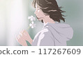 a young woman admiring and smelling the scent of flowers while there is sunlight shining down on a bright morning 117267609