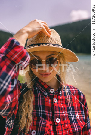 Woman traveler wearing hat and looking at amazing mountains and lake, wanderlust travel concept. black lake Montenegro. Woman traveler wearing hat and looking at amazing mountains and lake, wanderlust travel concept. black lake Montenegro. 117269952