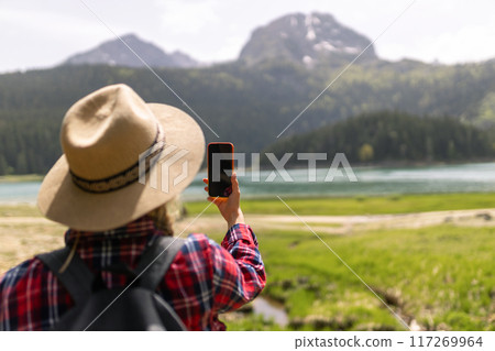 Selfie while traveling. Landscape with young woman, green hills and lake. Lifestyle, adventure, nature, active life. Selfie while traveling. Landscape with young woman, green hills and lake. Lifestyle, adventure, nature, active life. 117269964