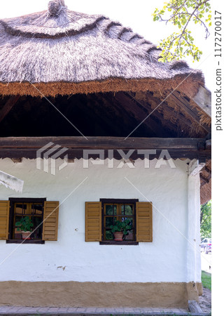 White old house with veranda and reed roof over blue sky White old house with veranda and reed roof over blue sky 117270017
