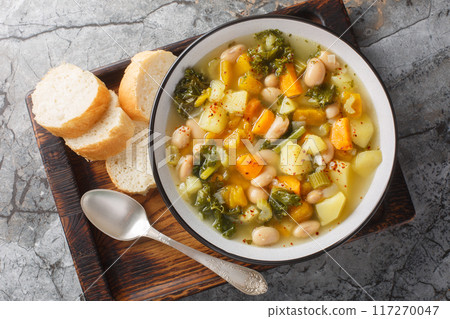Vegetable soup with beans, potatoes, pumpkin, kale, carrots, onions and celery close-up in a bowl. Horizontal top view Vegetable soup with beans, potatoes, pumpkin, kale, carrots, onions and celery close-up in a bowl. Horizontal top view 117270047