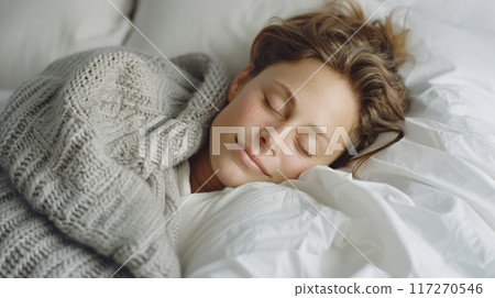Caucasian young woman is sleeping on bed with grey pillows and soft fabric blankets in modern white bedroom Caucasian young woman is sleeping on bed with grey pillows and soft fabric blankets in modern white bedroom 117270546