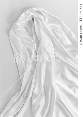 Close-up view of white fabric draped over gray surface. Smooth texture and pristine color with slight wrinkles add depth to scene. Fabric covers entire frame without background distractions. 117270723
