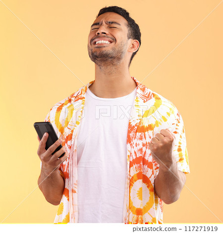 Winner, celebration and man with phone in studio isolated on yellow background. Winning, cellphone or happy male model holding mobile smartphone while celebrating goals achievement, target or success 117271919