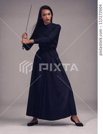 Samurai, sword and portrait of a ninja in a studio with a martial arts or assassin fighter skill. Fantasy, cosplay and female model in a warrior costume with a machete posing by a gray background. Samurai, sword and portrait of a ninja in a studio with a martial arts or assassin fighter skill. Fantasy, cosplay and female model in a warrior costume with a machete posing by a gray background. 117272004