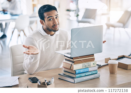 Confused, laptop and multitask with a business man shrugging his shoulders while working in the office. Desk, question and doubt with a male employee multitasking while at work on a stack of books 117272138