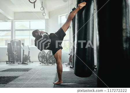 Professional, fit and active male fighter training with a punching bag in a gym. kickboxer practicing, training and fitness exercise for competitive fight, tournament or competition in a health club Professional, fit and active male fighter training with a punching bag in a gym. kickboxer practicing, training and fitness exercise for competitive fight, tournament or competition in a health club 117272222