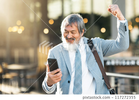 Happy businessman, winner or phone celebration for lottery, success corporate deal or financial company growth in city. Smile, fist pump or wow senior man winning online competition on smartphone app Happy businessman, winner or phone celebration for lottery, success corporate deal or financial company growth in city. Smile, fist pump or wow senior man winning online competition on smartphone app 117272355