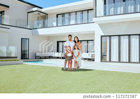 Family, children and real estate with a girl, parents and sister in the backyard of their home together. House, garden and property with a man, woman and kids standing on grass during the day Family, children and real estate with a girl, parents and sister in the backyard of their home together. House, garden and property with a man, woman and kids standing on grass during the day 117272387