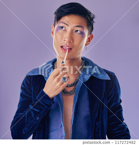 Beauty, makeup and lgbt Asian man in studio on purple background using cosmetics, beauty products and lipstick. Creative, fashion and queer or lgbtq male model with lip gloss, eyeshadow and style 117272482