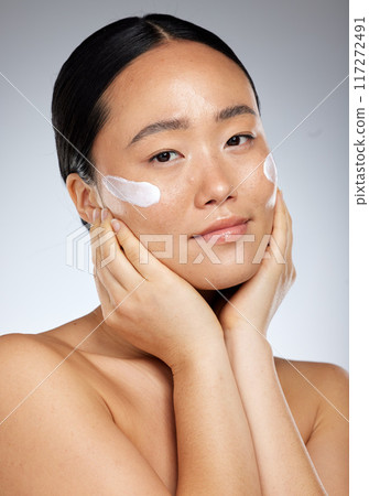 Beauty, asian skincare and woman using face cream or dermatology product for healthy and clean skin. Studio portrait of happy girl model feeling luxury facial or daily cosmetics routine results 117272491