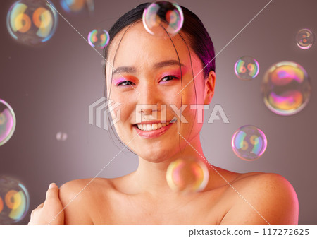 Makeup, bubbles and Asian woman with smile, for cosmetics, skincare or health on a studio background. Portrait of a young girl with body care, natural beauty or happiness for organic facial 117272625