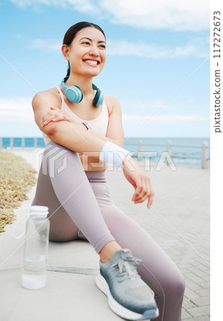 Fitness woman, happy and beach exercise while taking break or rest while out running on promenade with a positive mindset, motivation and goal. Happy asian athlete girl runner outdoor for a workout 117272673