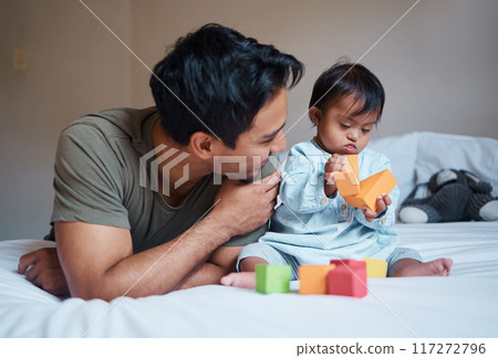 Father and down syndrome baby play education game with toys on bed for growth and happy together. Man smile in bedroom with toddler boy, learning color and development in home with building blocks Father and down syndrome baby play education game with toys on bed for growth and happy together. Man smile in bedroom with toddler boy, learning color and development in home with building blocks 117272796