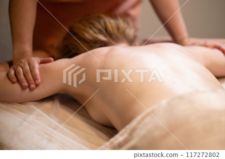 Massage therapist with client. Massage for a healthy body. Hands of a masseur on a woman's body 117272802