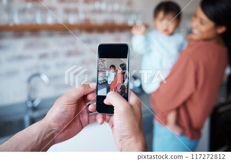 Father taking a picture of mother and baby on a phone in the kitchen of their family house. Love, care and man taking photo on smartphone of a happy and proud mom bonding with her child in their home Father taking a picture of mother and baby on a phone in the kitchen of their family house. Love, care and man taking photo on smartphone of a happy and proud mom bonding with her child in their home 117272812