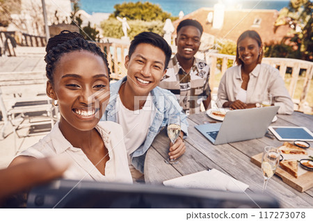 Group of business people taking a selfie at a restaurant having a lunch meeting outdoors in a city. Colleagues or friends take a picture or a photo while on a break from work having brunch at a cafe 117273078