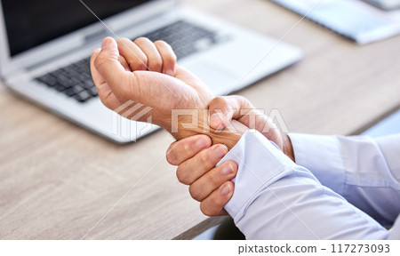 Business man with bad wrist pain in the hand after an injury and ache while in the office. Closeup of a corporate male with a painful strain, hurtful and sore sitting at his desk Business man with bad wrist pain in the hand after an injury and ache while in the office. Closeup of a corporate male with a painful strain, hurtful and sore sitting at his desk 117273093