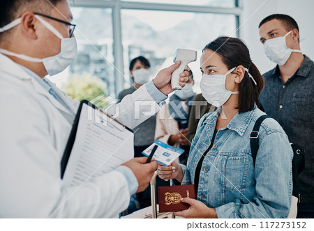 Travel restriction, covid pandemic and temperature check at airport. Asian female wearing mask for corona virus prevention waiting in departure inspection line, doctor pointing digital thermometer. Travel restriction, covid pandemic and temperature check at airport. Asian female wearing mask for corona virus prevention waiting in departure inspection line, doctor pointing digital thermometer. 117273152