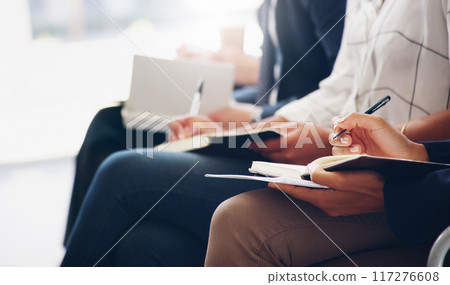 Note taking is vital for success. Cropped shot of unrecognizable businesspeople sitting and writing notes in a book while in the office during the day. 117276608