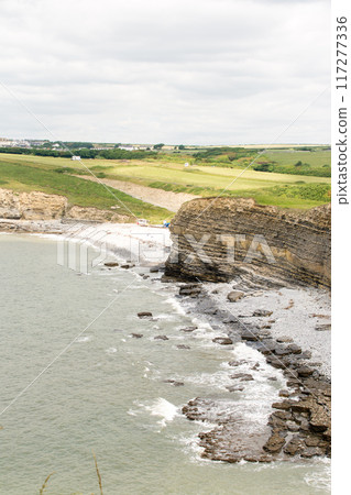 A coastline of gravel and a cove with cliffs formed by seawater erosion. On the outskirts of South Wales. A coastline of gravel and a cove with cliffs formed by seawater erosion. On the outskirts of South Wales. 117277336