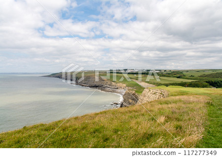 A coastline of gravel and a cove with cliffs formed by seawater erosion. On the outskirts of South Wales. A coastline of gravel and a cove with cliffs formed by seawater erosion. On the outskirts of South Wales. 117277349