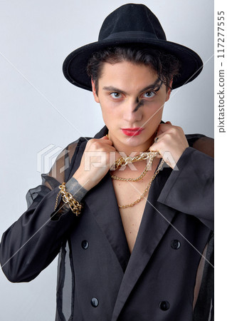 Serious young transgender man LGBTQ being as woman posing with chain, in hat 117277555