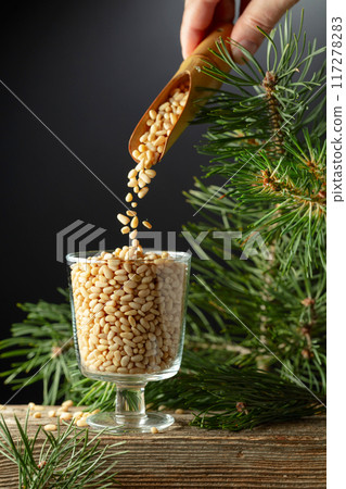 Pine nuts is poured in a glass bowl. Pine nuts is poured in a glass bowl. 117278283