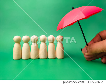 Hand holding red umbrella with peg doll arrangement to protect wooden peg doll, plan, save family, prevent risk and crisis, health care and insurance concept. 117278634