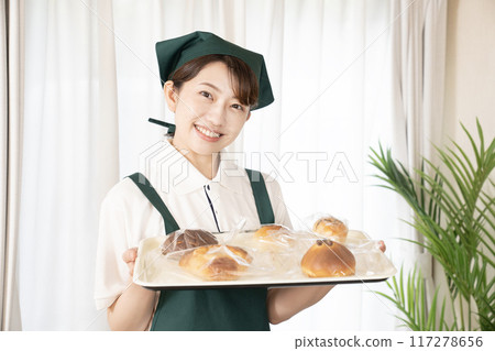 Female bakery staff holding freshly baked bread Female bakery staff holding freshly baked bread 117278656