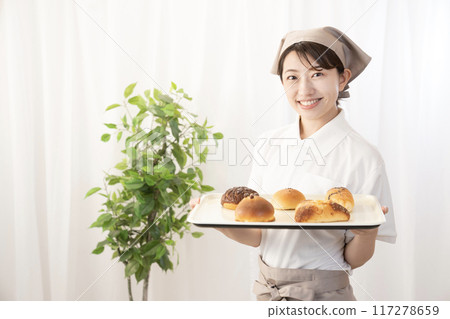 Female bakery staff holding freshly baked bread 117278659