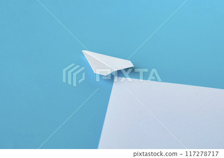 Angle view of white paper airplane flying along the route on blue background Angle view of white paper airplane flying along the route on blue background 117278717
