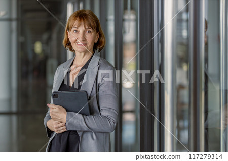 Portrait of middle aged woman company HR holding digital tablet wearing black suit 117279314