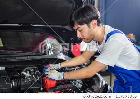 Repairman using handheld digital multimeter of car engine auto mechanic checking battery power  117279316