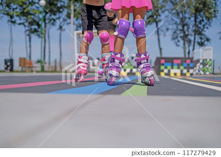 Close-up of roller skates of girls riding in a skate park on a sunny summer day Close-up of roller skates of girls riding in a skate park on a sunny summer day 117279429