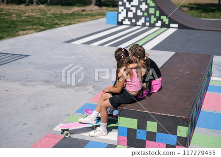 Cute girls relax on the bench of the skatepark after skateboarding 117279435